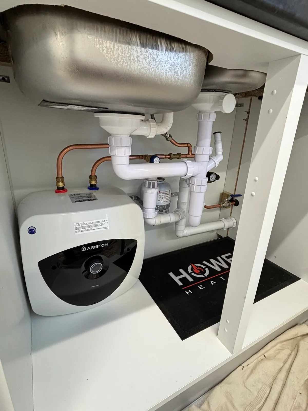 Stainless steel unvented cylinder and Ariston water heater installed by Howe Heating with a clean finish